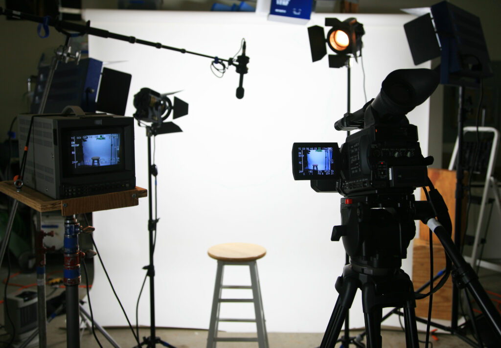 Video production equipment including video camera, monitor, lights, microphone, background and stool for filming training video