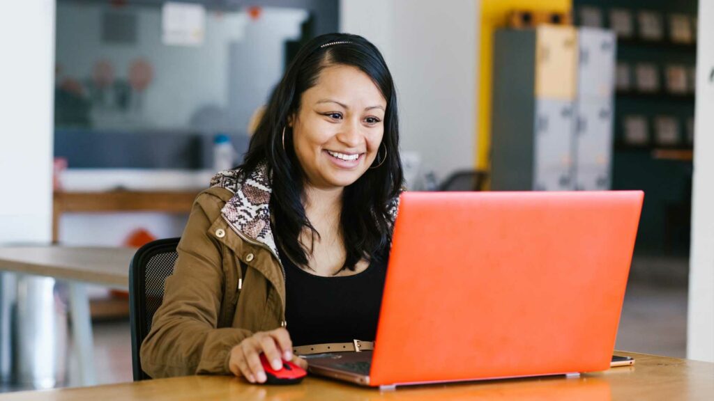 Women on orange laptop using SalexLMS video-based training.